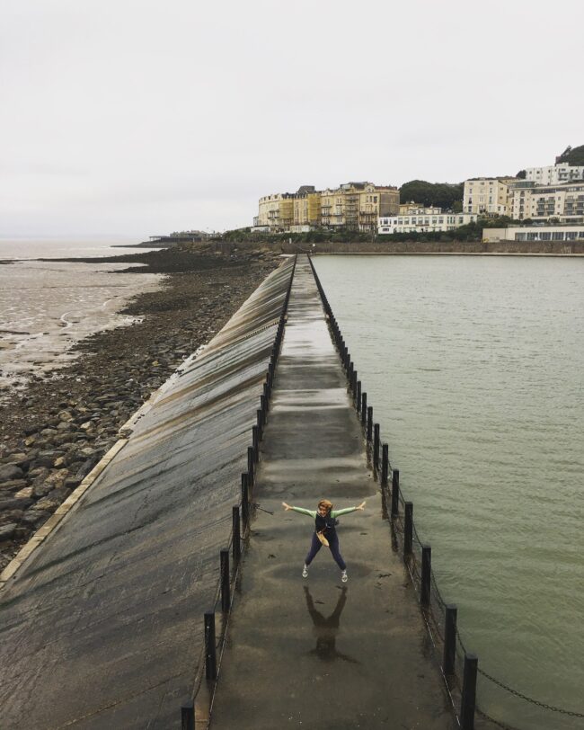Liz Liz standing on a walkway in between the sea and reservoir