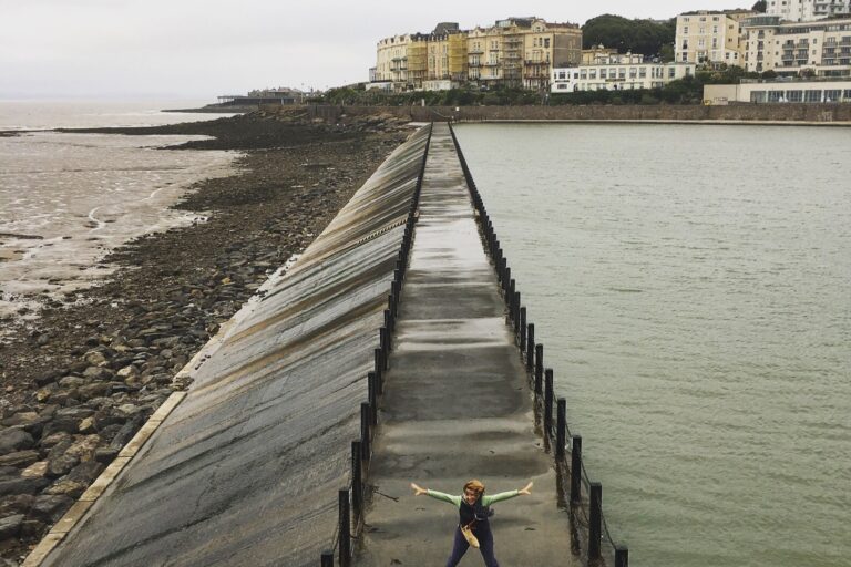 Liz standing on a walkway in between the sea and reservoir