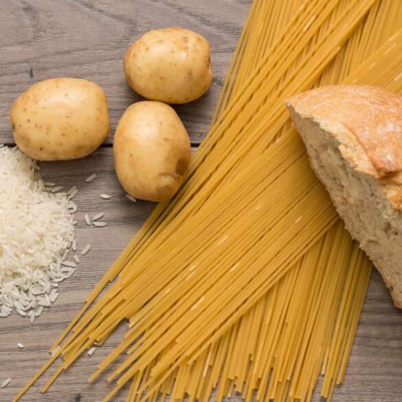Spaghetti, rice, potatoes, and bread, on a wooden table