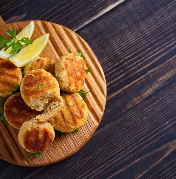 Fish cakes with lemon and herbs. Fish patties on wooden board. Overhead, horizontal image