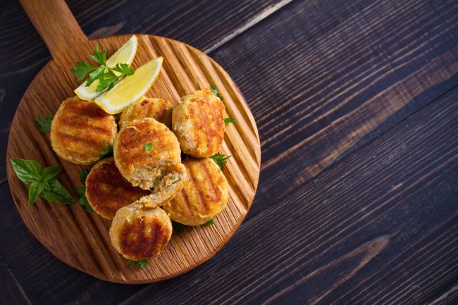 Fish cakes with lemon and herbs. Fish patties on wooden board