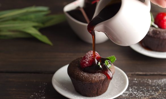 Syrup pouring on Coulant or Chocolate fondant decorated with raspberry, mint  and powdered sugar. Delicious french dessert