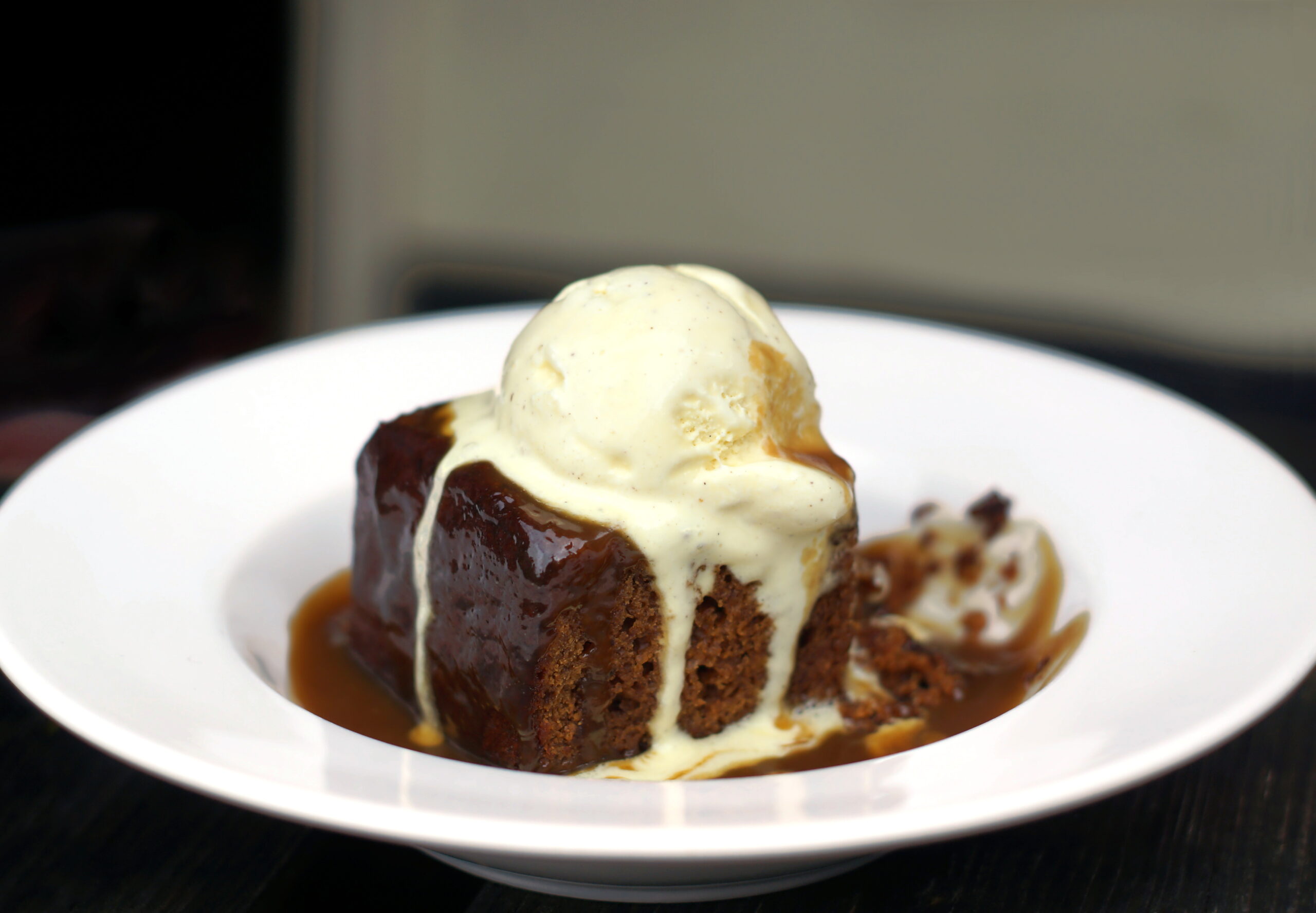 Sticky toffee pudding with ice cream drizzled on top.