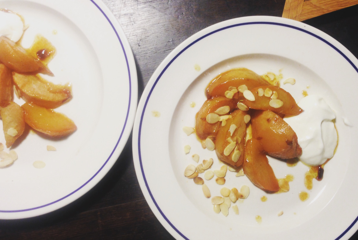 Buttery roasted comice pears with flaked almonds on a white plate