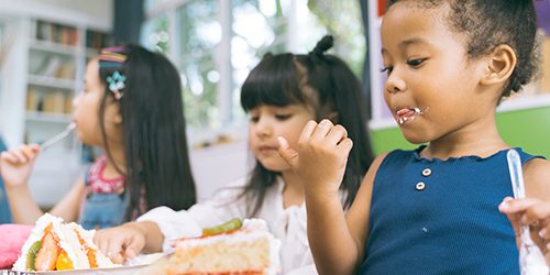 cute little child girl with diversity friends eating cake togeth