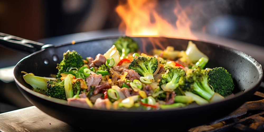 close-up of beef and broccoli stir-fry in a wok on high flame
