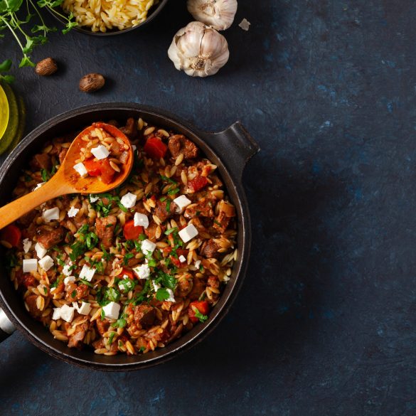 Traditional Greek cuisine. Lamb stew with feta cheese and vegetables. Dark background.