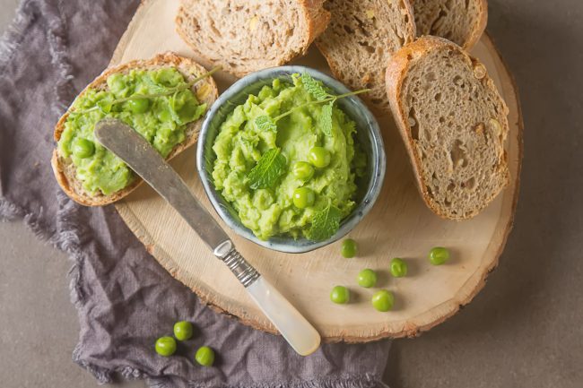 Baguette with mashed green peas and mint. Dark background. Selective focus. Top view