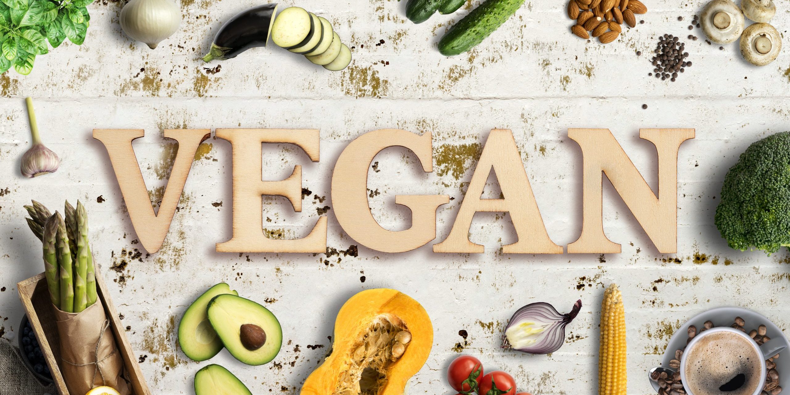 Word “vegan” in wooden letters with many cooking ingredients
