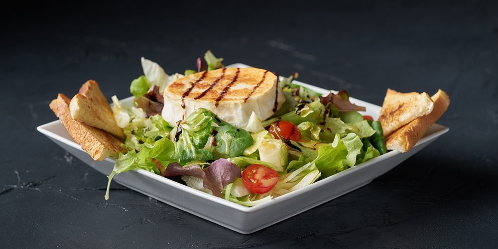 Fresh green healthy salad with grilled goat cheese chevre isolat