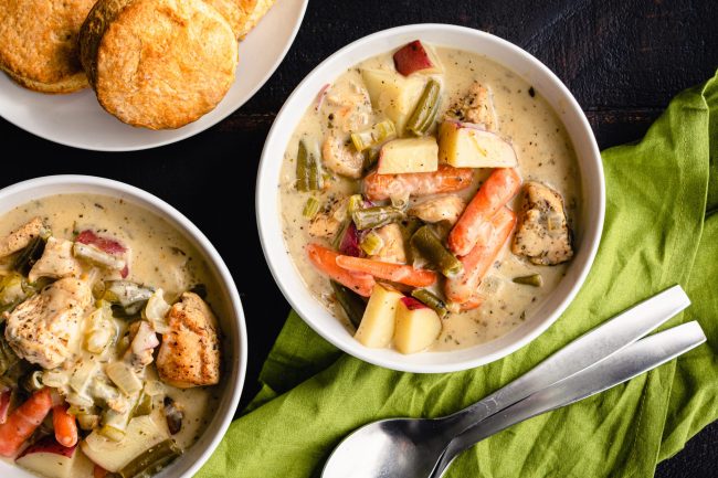 Bowls of Creamy Chicken Stew Served with Biscuits: Chicken and vegetable stew served with biscuits on the side