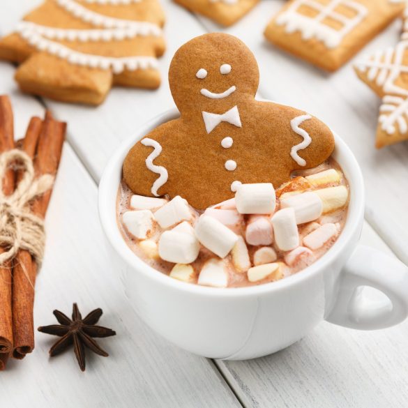 Sweet Christmas composition. Gingerbread cookie in cup of hot chocolate on white table