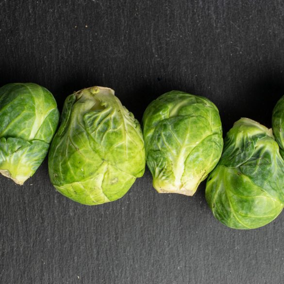 Group of six whole fresh green brussels sprout flatlay on grey stone