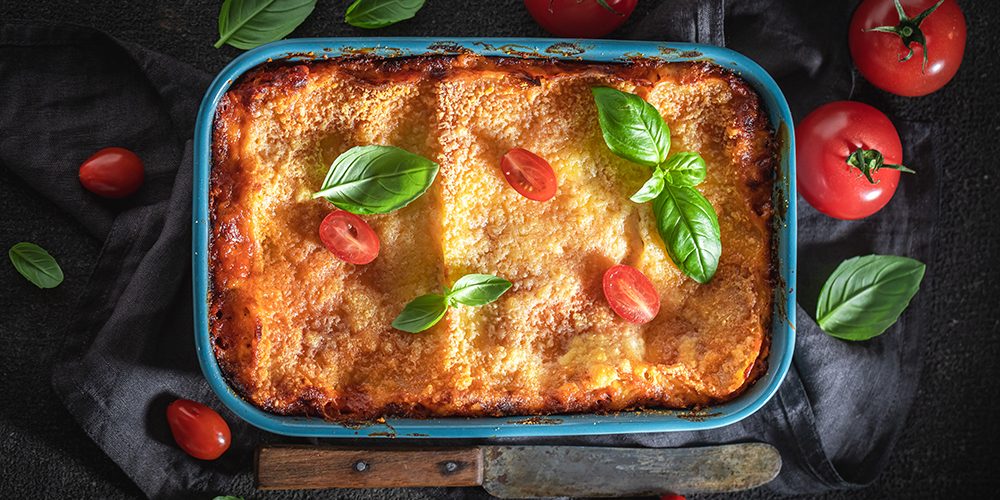 Hot lasagna with bechamel sauce, tomatoes and herbs