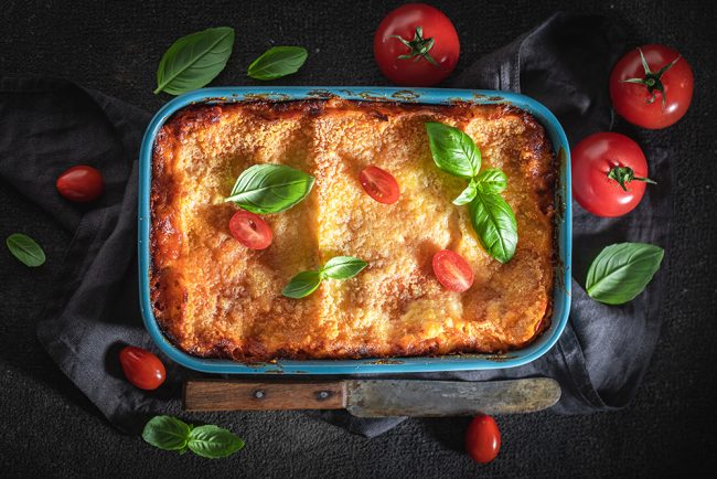 Hot lasagna with bechamel sauce, tomatoes and herbs