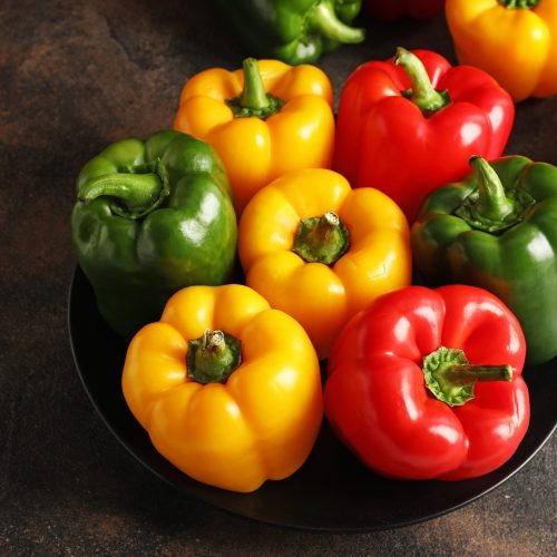 Fresh bell peppers in plate on table