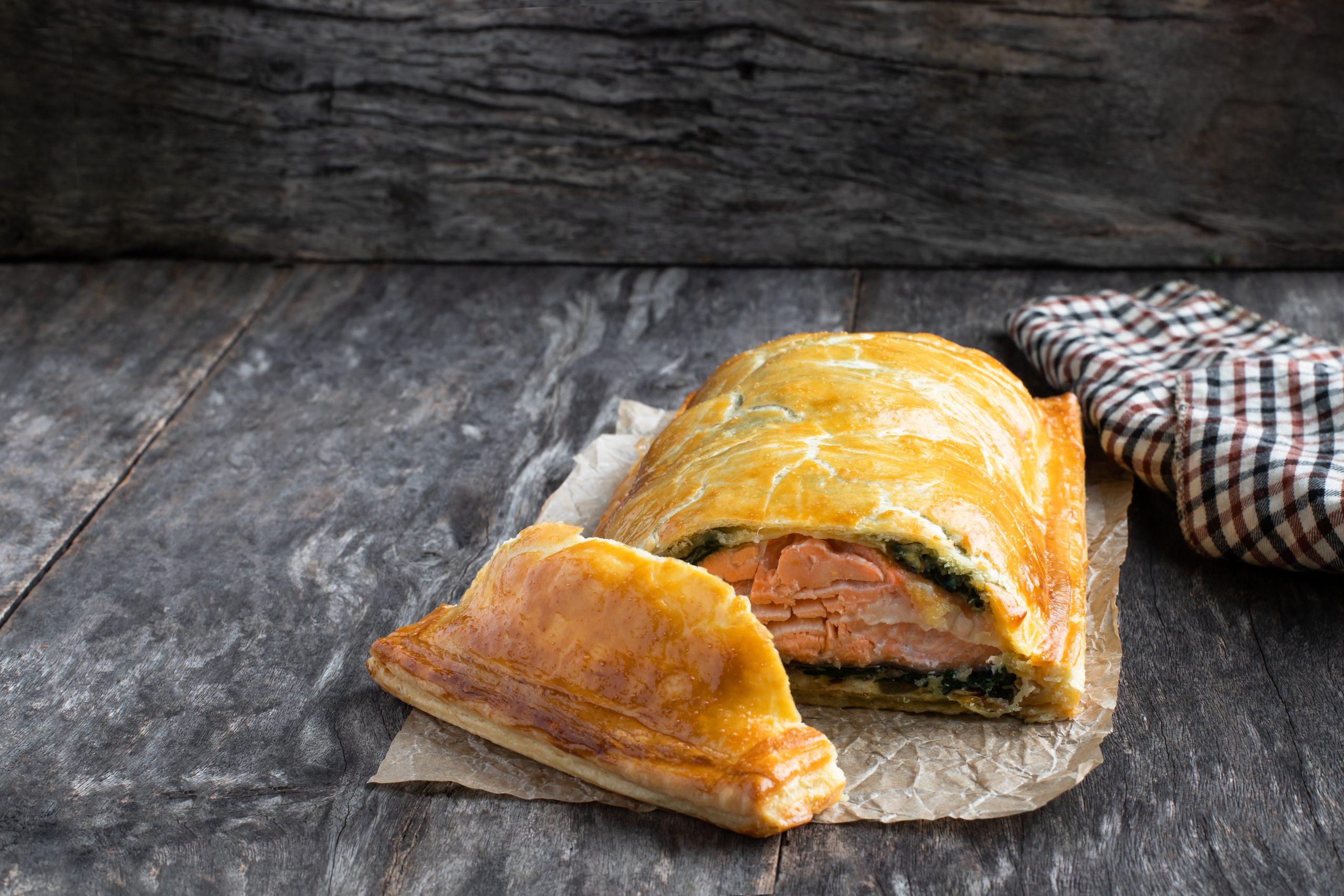Homemade salmon wellington with spinach and mushrooms on rustic