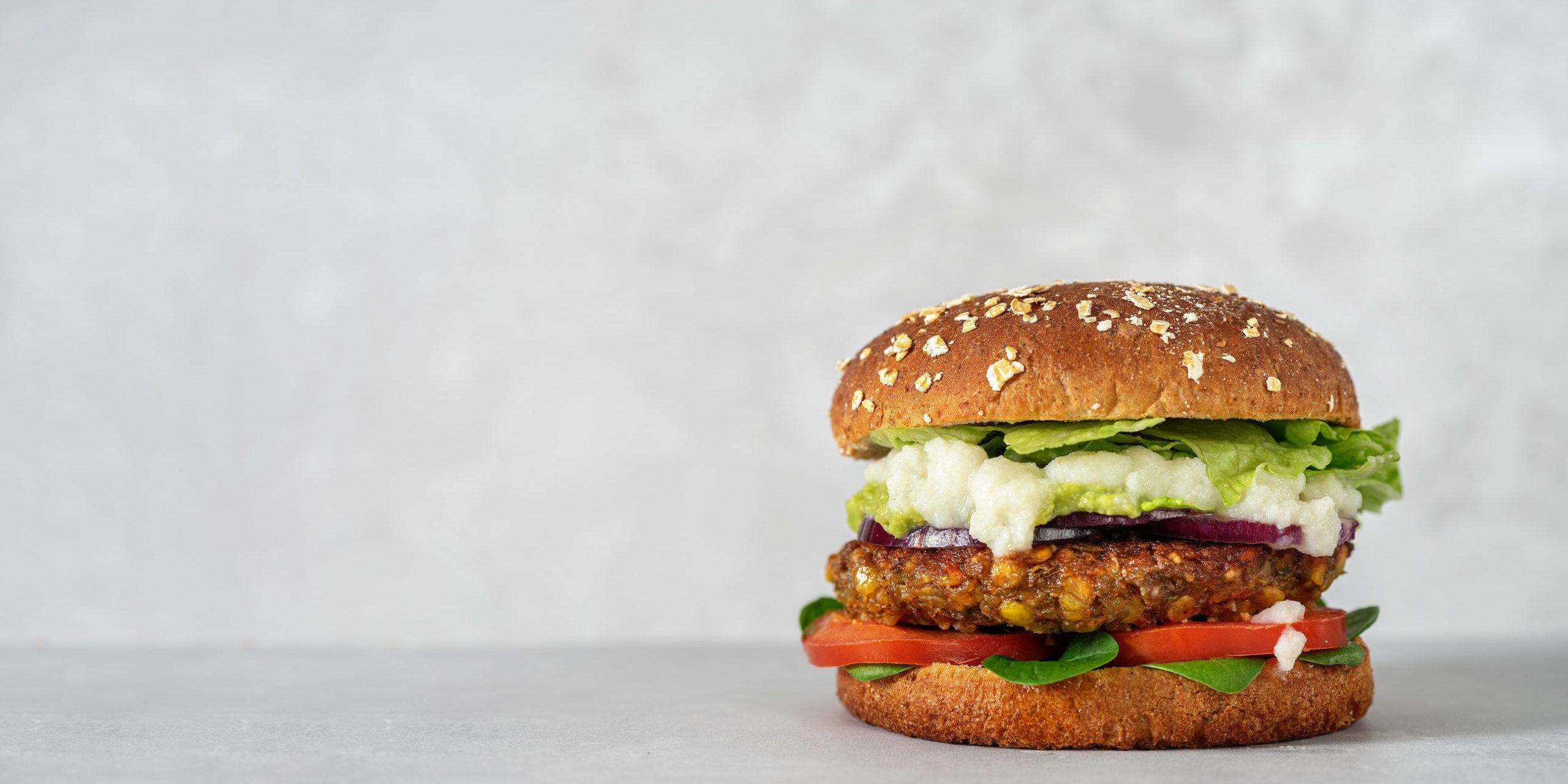 Vegan lentils burger with vegetables on light gray background