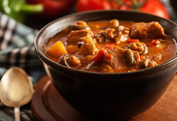 Stew soup with meat, potatoes, mushrooms and red pepper in bowl