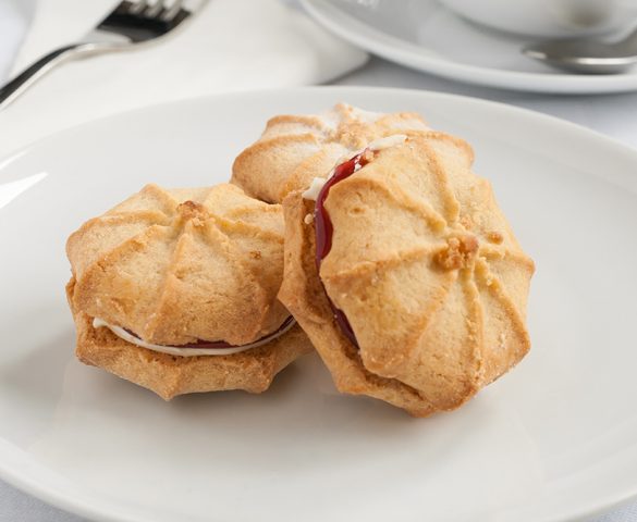 An afternoon tea table setting with Viennese whirls on white porcelain.