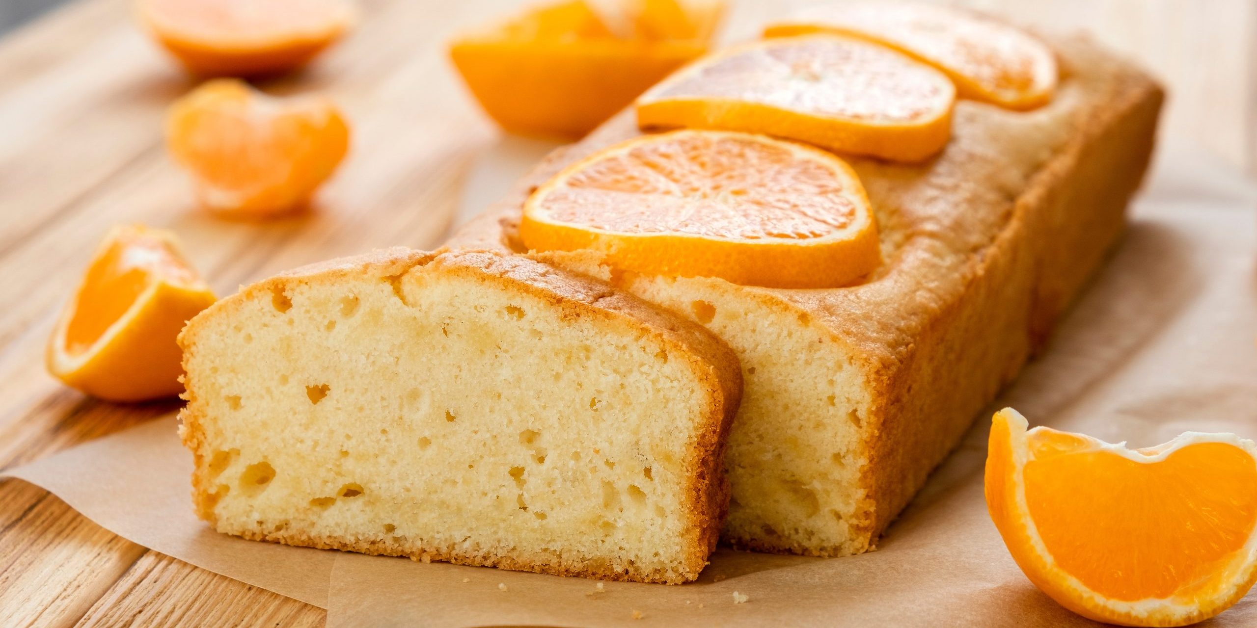 Loaf of gluten free tangerine cake with pieces of mandarin on rustic wooden background. Close up slice of citrus pie by classic recipe. Healthy nutrition, homemade vegan dessert.