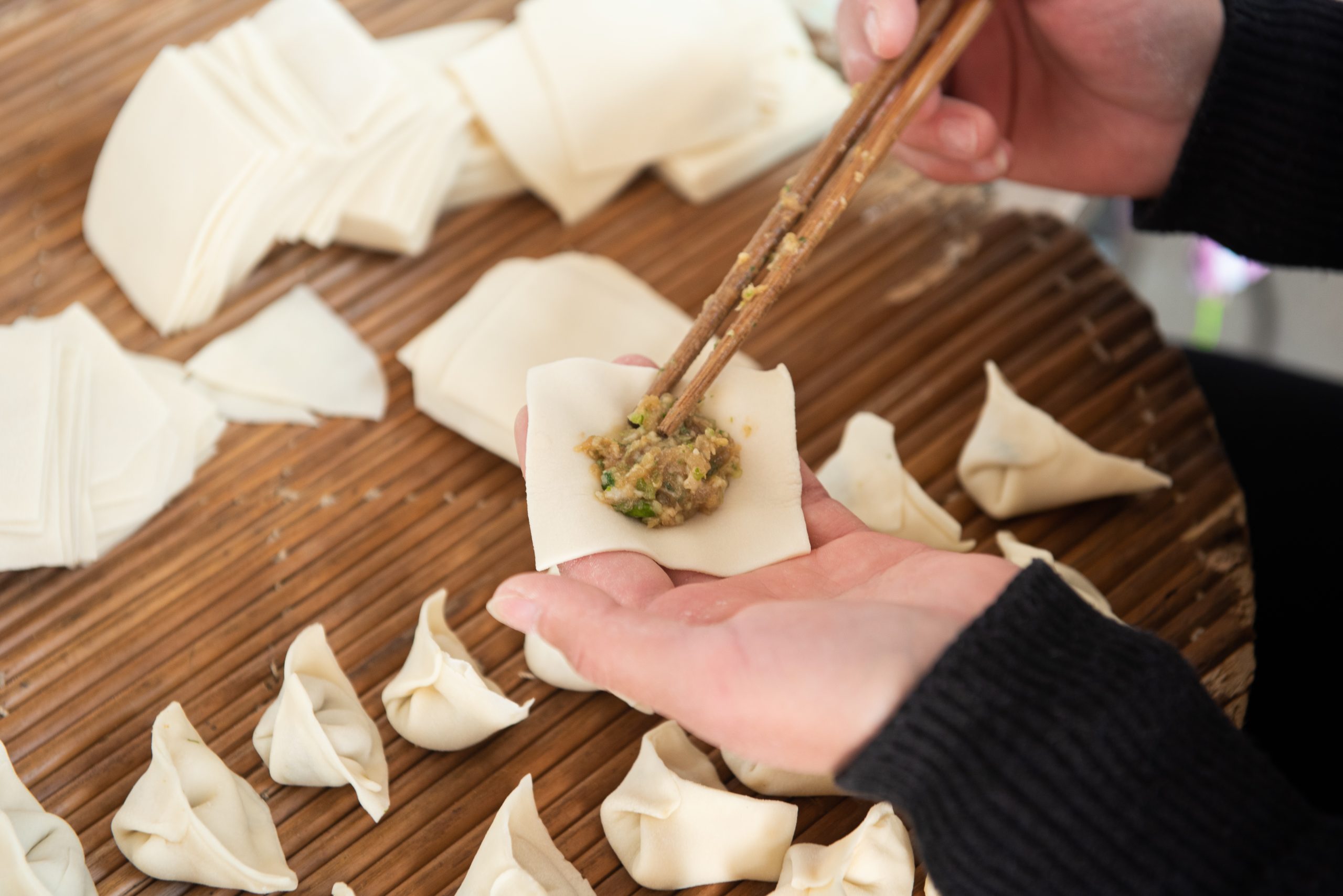 Chopsticks sandwich the meat into the dumpling wrapper to make d