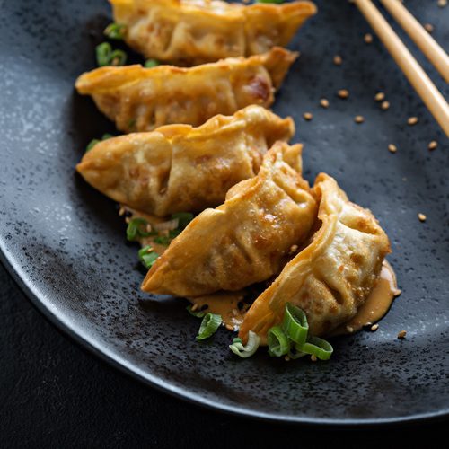 Fried potstickers with green onions on black plate