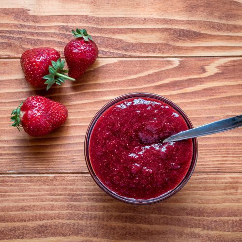 Homemade strawberry jam in a a glass bowl with fresh ripe strawb