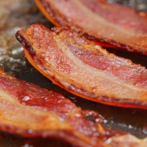Fry bacon in pan in kitchen