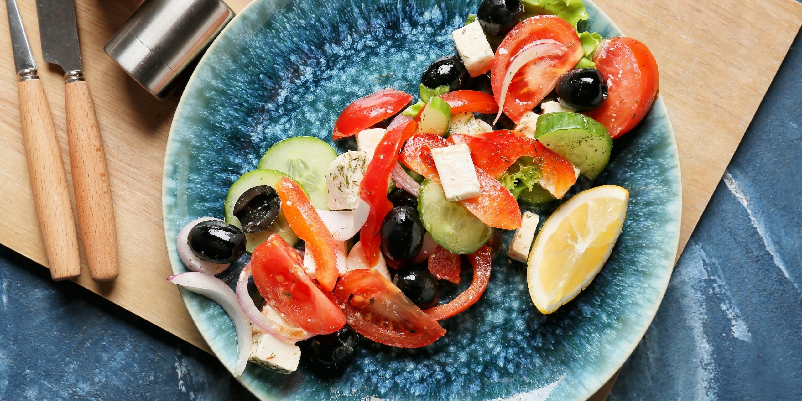 Plate of fresh Greek salad on color background