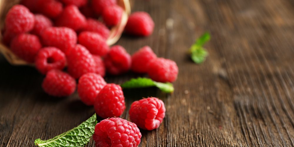 Fresh red raspberries on wooden table, closeup