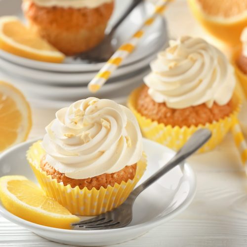 Plate with delicious lemon cupcake on white table