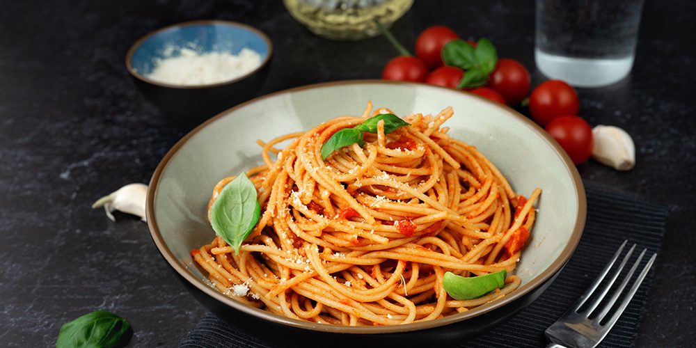 Pasta in a plate with tomato sauce on black background