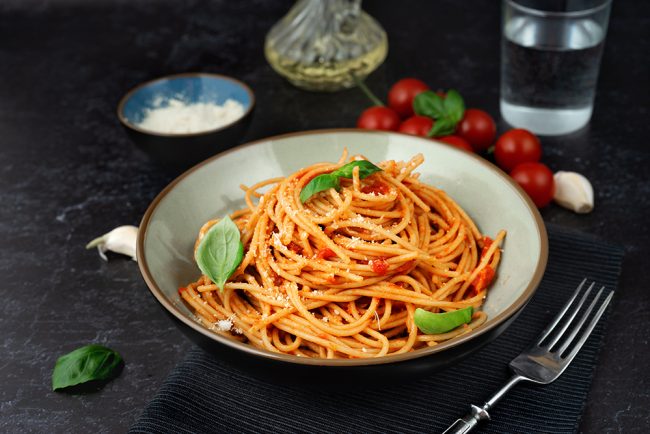 Pasta in a plate with tomato sauce on black background