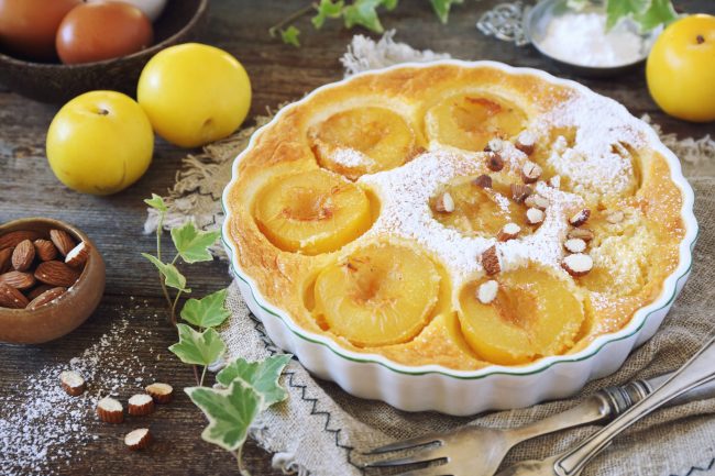 Yellow plums clafoutis (flan) with almonds, icing sugar dressing