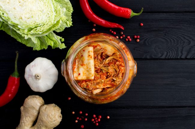 Kimchi in the glass jar and ingredients on the black wooden  bac