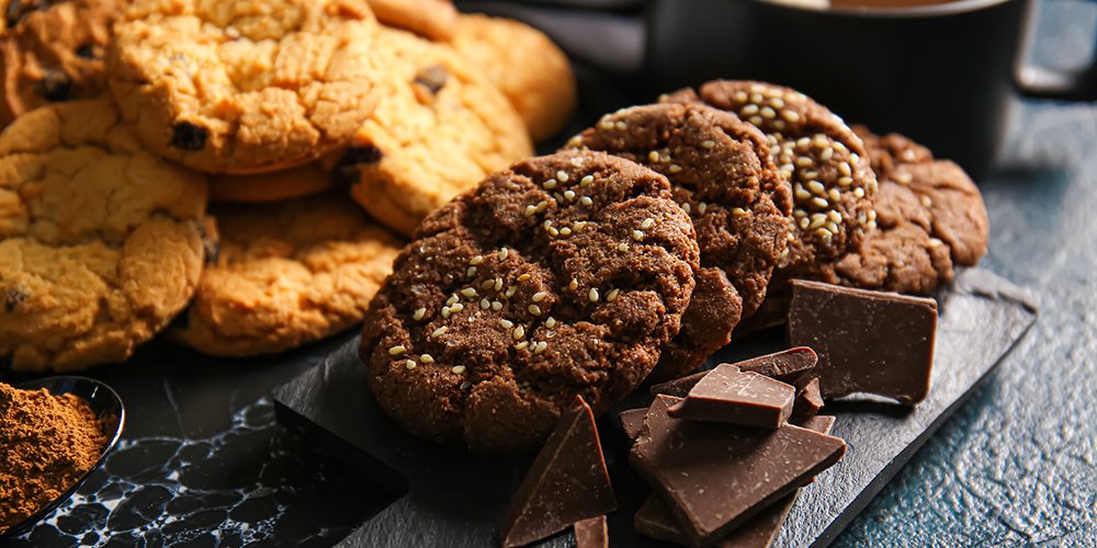 Board with tasty chocolate homemade cookies on black background