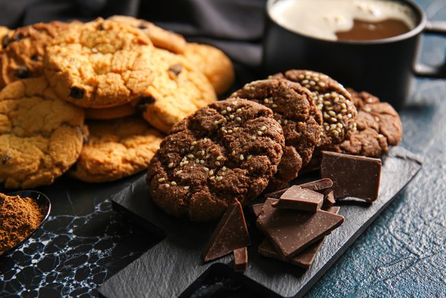 Board with tasty chocolate homemade cookies on black background