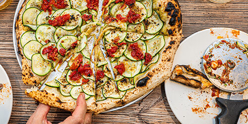 Neapolitan zucchini pizza on a rustic wooden table