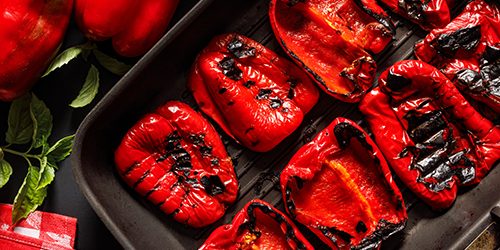 Grilled red peppers on a grill plate close up view