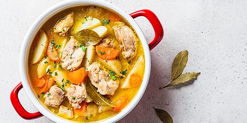 Chicken stew with potatoes and carrots in red saucepan. Chicken