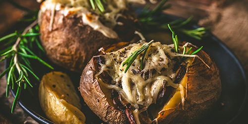 Baked potatoes with mushrooms, sour cream and cheese on a rustic