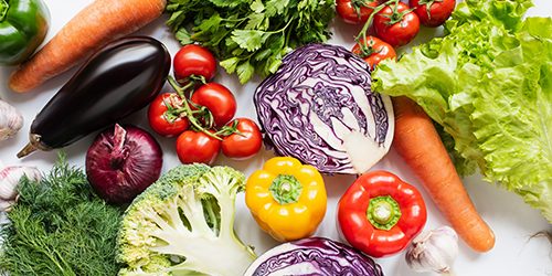 top view of assorted fresh vegetables on white background