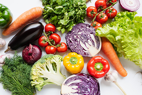 top view of assorted fresh vegetables on white background