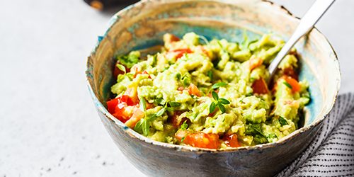 Fresh avocado tomato guacamole in a bowl. Healthy plant based fo