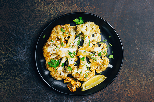 Fried cauliflower steak with greens and spices.