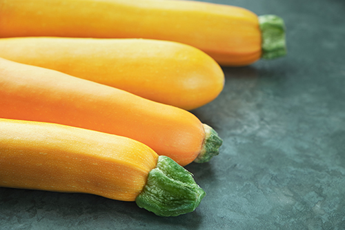 Four yellow zucchini on kitchen table. Whole raw courgettes