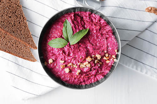 Bowl of fresh beet hummus on table