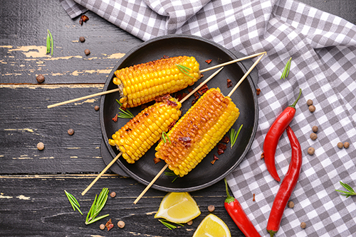 Plate with tasty grilled corn cobs on table